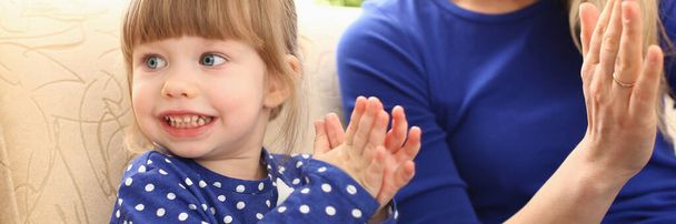 Cute little girl plays with mom and claps hands. Home games with young children concept - 写真・画像
