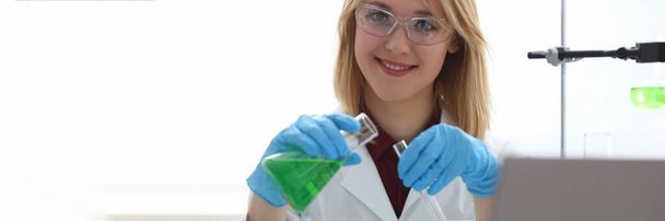 Scientist holds bottle with sample with toxic green liquid in hands in protective gloves. Toxic substances and liquids concept - Fotoğraf, Görsel