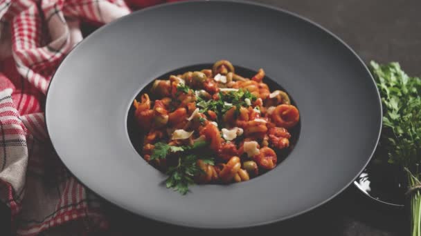 Tasty appetizing classic italian pasta with tomato sauce, cheese parmesan and basil on plate on dark table. View from above flat lay - Metraje, vídeo