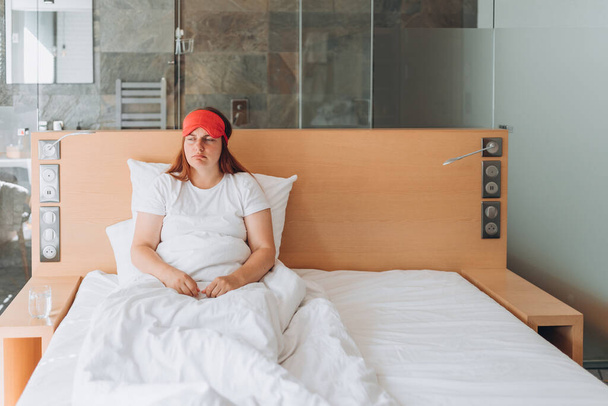 Young girl with funny face sick or sad depressed sleeping at home. Millennial woman wake up in cozy white bed in modern apartment in the morning. - Fotoğraf, Görsel