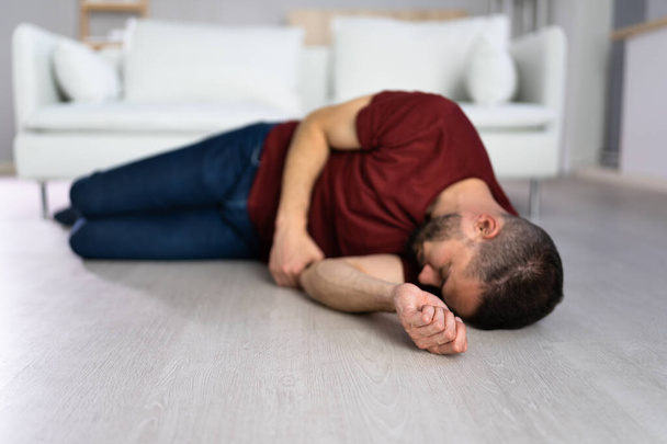Unconscious Young Man Lying On Floor In Living Room - Foto, afbeelding