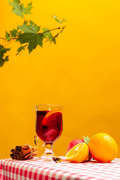 Glass with delicious aromatic cocktail, mulled wine with orange slice and cinnamon stick isolated on yellow background. Concept of taste, drink, healthy ingredients, seasonal drink. Copy space for ad - Fotografie, Obrázek