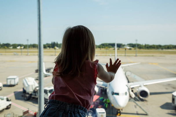 Klein meisje kijkt vliegtuig op de luchthaven - Foto, afbeelding