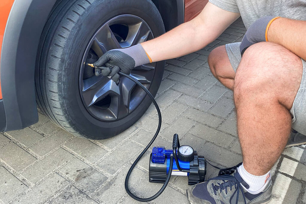 Car service. Male hand in gloves checks pressure in car tires in sunny day. - Photo, Image