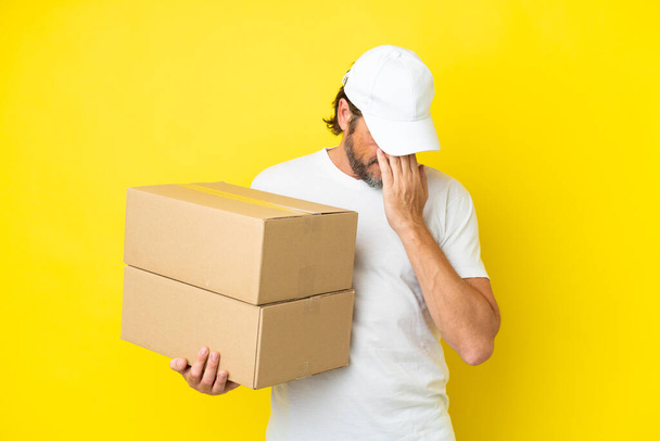Delivery senior dutch man isolated on yellow background with tired and sick expression - Photo, Image