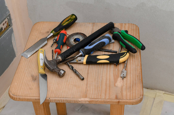 outils de travail se trouvent dans un ordre chaotique sur la chaise, réparations dans la maison, une variété d'outils. - Photo, image