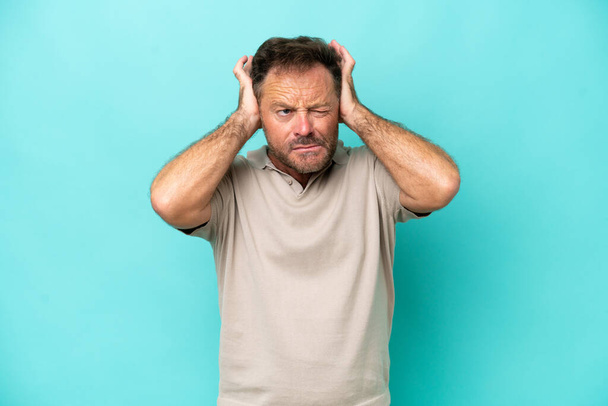 Middle age caucasian man isolated on blue background frustrated and covering ears - Fotó, kép