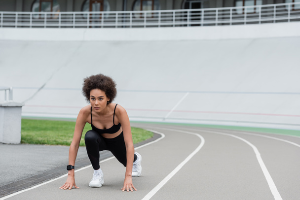 young african american jogger standing in low start pose on track - Photo, image