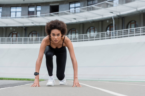 front view of african american woman in sportswear and fitness tracker standing in low start pose - Photo, Image