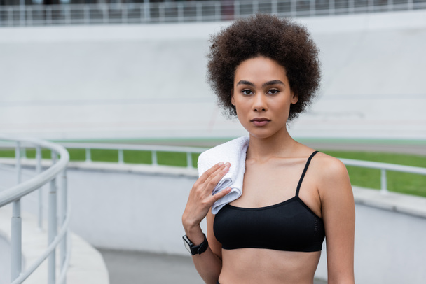 young african american woman in fitness tracker standing with white towel on shoulder - Foto, Imagen