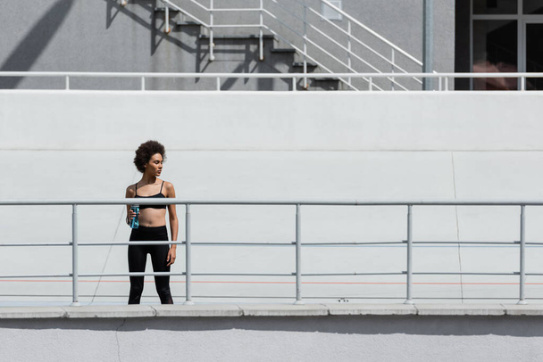 young african american sportswoman standing with sports bottle on city stadium - Foto, immagini
