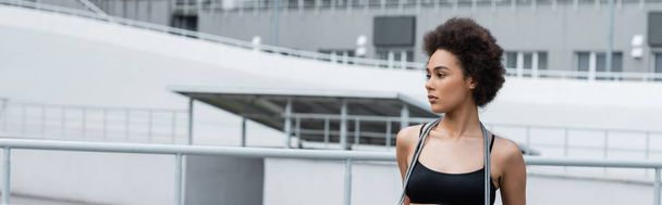 Young african american sportswoman with jump rope on neck standing on stadium, banner  - Foto, Imagen