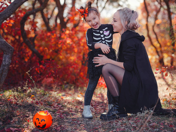 Mother and her child girl playing together. goes trick or treating. Little witch, Kids with jack-o-lantern. Children with candy bucket in fall forest. Happy Halloween. - Foto, immagini