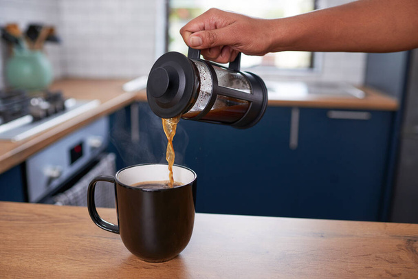 Крупный план ручного наливания свежего фильтрующего кофе в кружку на чистой кухне. Высокое качество фото - Фото, изображение