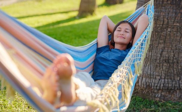 young beautiful lady posing while lying on hammock, beautiful asian woman, brunette resting on vacation, relax, outdoor portrait. long weekend and vacation holidays spent slow life in Turkey - Photo, image