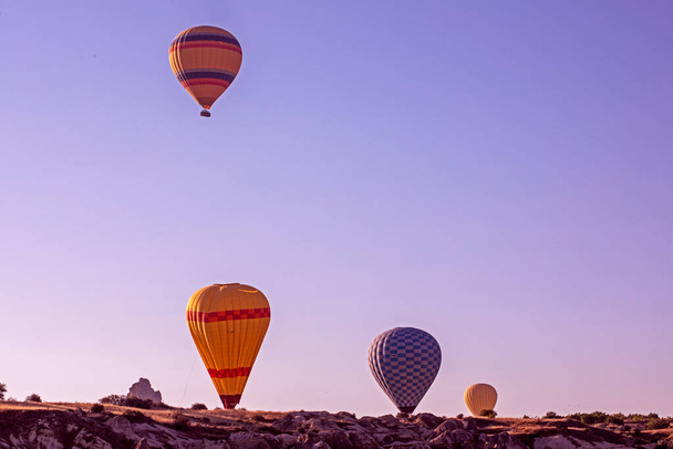 many colorful balloons land on the goreme hills in Cappadocia in the early morning. Hot air balloon tourism - Foto, Bild