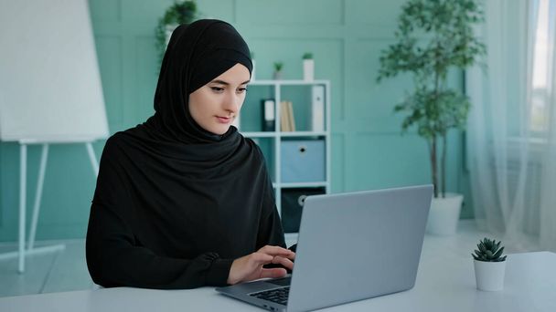 Ocupado Islam mujer de negocios en negro hijab freelancer árabe islámico chica estudiante trabajador musulmán mujer con portátil de trabajo e-learning escribiendo chat en línea aplicación de comercio electrónico de navegación web en red - Foto, imagen