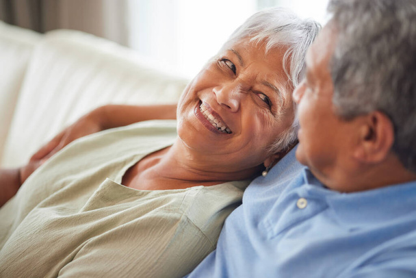 Happy, love and smile senior couple hugging relax and sitting on a couch at home. Man and woman lovers smiling and enjoying quality bonding together in the living room and having fun in the house. - Photo, image