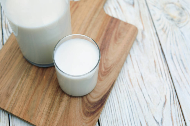 Bottle and glass of tasty fresh milk on white wooden table, closeup. Space for text - Φωτογραφία, εικόνα