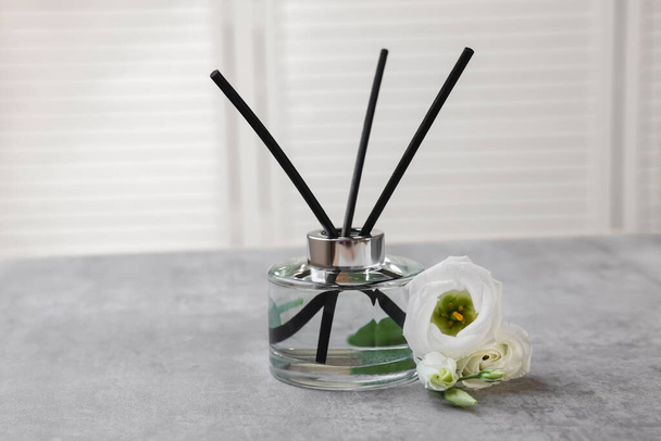 Reed diffuser and eustoma flowers on gray marble table - Foto, Imagen