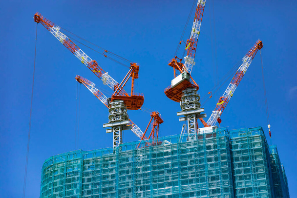 Cranes at the under construction daytime long shot. High quality photo. Minato district Iikurakatamachi Tokyo Japan 08.09.2022 It is center of the city in Tokyo. - Foto, Imagen
