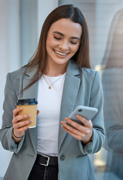 Business woman communication on phone with social media app, web internet technology and coffee cup break in startup company. Happy, smile and content office worker reading funny mobile notification. - Foto, immagini