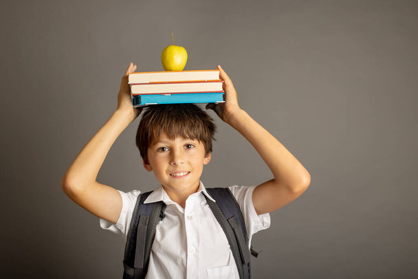 Cute preschool blond child, boy, holding books and notebook, apple, wearing glasses, ready to go to school - Φωτογραφία, εικόνα
