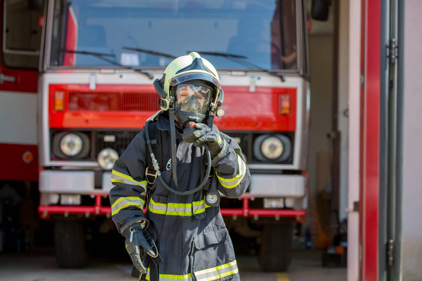 Child, cute boy, dressed in fire fighers cloths in a fire station with fire truck, childs dream - Foto, Bild