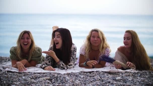Beach picnic - four women lying on the blanket. Mid shot - Imágenes, Vídeo