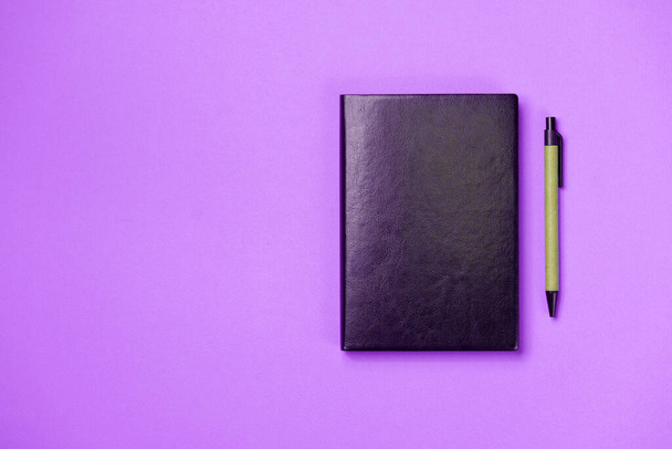 Black leather notebook on a paper pink background, notepad mock up, top view shot - Foto, Bild