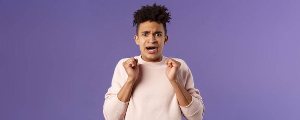 Close-up portrait of worried, anxious funny hispanic man jumping from fear, gasping look concerned, starting to panic before important meeting, standing purple background afraid and nervous. - Photo, Image