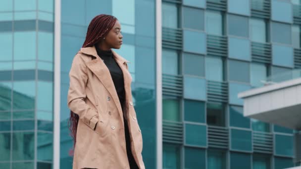 Young stylish woman looks away waiting for meeting stands in business center of city confident successful serious businesswoman turns to camera fashion girl model posing outdoors looking at camera - Footage, Video