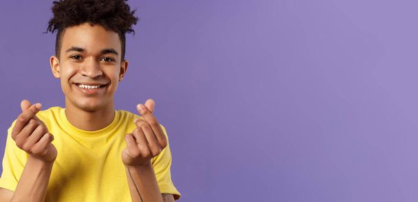 Lähikuva muotokuva ihana söpö nuori mies afro kampaus, osoittaa korealainen sydän sormi merkkejä ja hymyillen, ilmaista rakkautensa ja myötätuntonsa henkilöä kohtaan, seistä violetti tausta
. - Valokuva, kuva