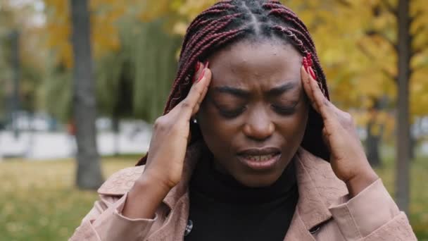 Close-up unhealthy frustrated woman holding head suffering from headache feels burning pain squeezing pressure suffers from chronic migraine unhappy girl stands outdoors feeling symptom of illness - Video