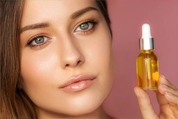 Beauty, makeup and skincare cosmetics model face portrait, woman holding skin care cosmetic essential oil bottle with dropper, luxury facial care product mockup - Foto, Imagem