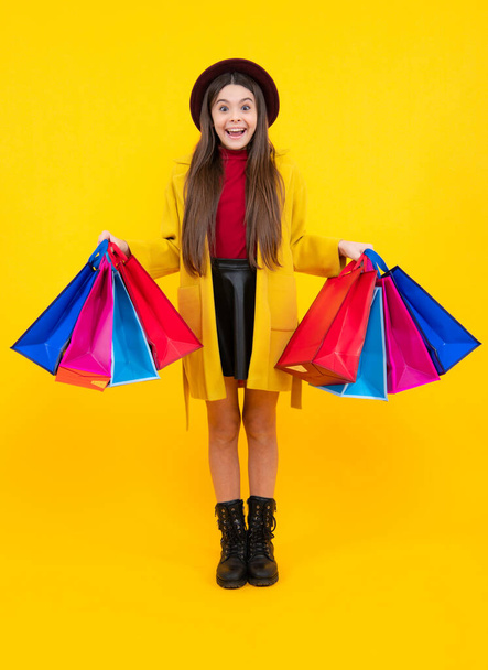 Sale and shopping concept. Teen girl holding shopping bags, isolated on studio background. Winter shopping sale. Excited teenager, glad amazed and overjoyed emotions - Photo, Image