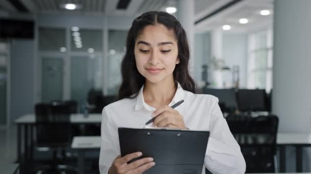 Young woman secretary writes down details of task writing data in clipboard makes daily appointments cute girl trainee listens to supervisor takes notes creates business ideas making poll in office - Video