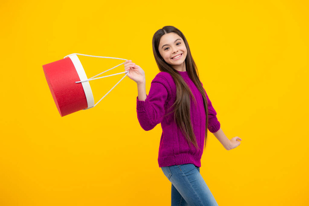 Child girl hold shopping bag enjoying sale isolated on yellow background. Portrait of teenager girl is ready to go shopping - Photo, Image