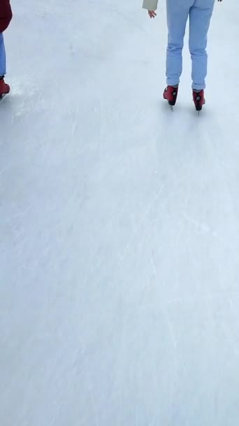People skating on public open-air ice skating rink in city on winter day. People skating on ice rink. Legs, back, ice rink. Winter holidays, activities ,recreation ,rest, sport. Vertical video - Imágenes, Vídeo