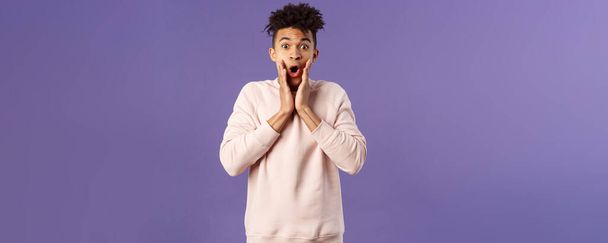 Oh my gosh. Portrait of amazed, speechless excited hispanic guy staring overwhelmed at something stunning, watching incredible performance, react shocked and amazed, purple background. - Foto, afbeelding
