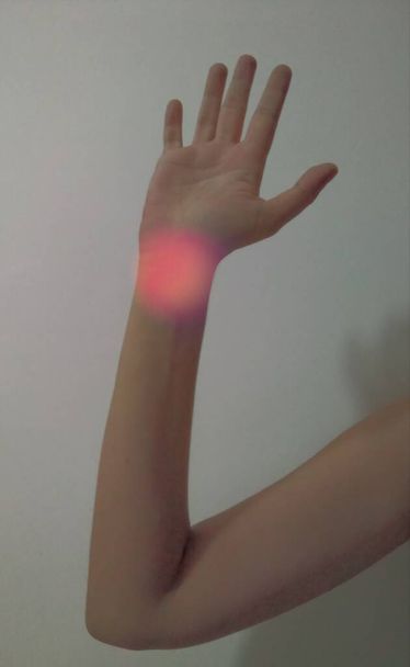 Female arm. There is a red round light on the wrist. A good example for the healthcare industry. Body part. - Fotó, kép