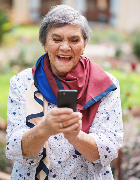 Щаслива старша жінка, використовуючи смс-повідомлення смартфона на мобільному телефоні в прекрасному саду
. - Фото, зображення