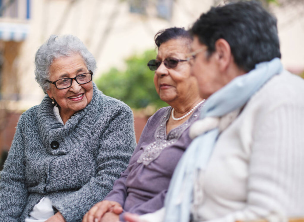 Happy elderly women sitting on bench in park smiling best friends enjoying retirement together. - Foto, afbeelding