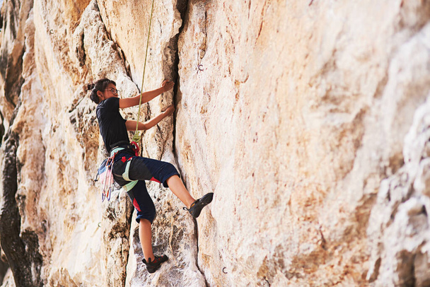 Courage will take you further. a young rock climber scaling a cliff face - Foto, immagini