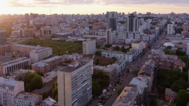 Aerial view of city buildings with car traffic during sunset. Urban cityscape background. - Materiaali, video