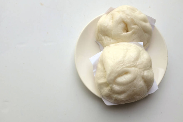 πάνω άποψη και επίπεδη θέσει δύο γεμιστά νόστιμα ένα χοιρινό στον ατμό ψωμάκια σε λευκό πιάτο απομονώσει σε λευκό φόντο - Φωτογραφία, εικόνα