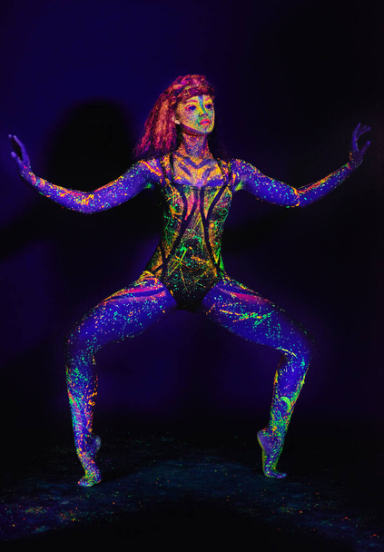 Highlighting her movement. Full length shot of a young woman posing with neon paint on her face - Fotoğraf, Görsel