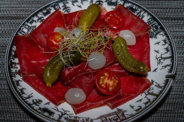 Sliced dried meat, pickled cucumber and onions. Food appetizer concept. Traditional Swiss food. Delicious. - Foto, afbeelding