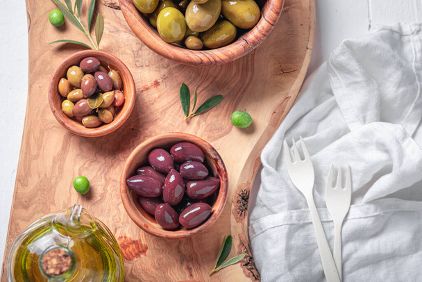 Tasty olives and extra virgin olive oil as Italian appetizer. Set of green and black olives in wooden bowls. - Foto, Imagem