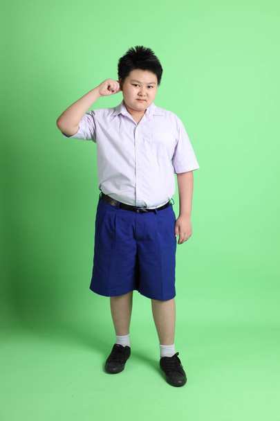 The Asian boy with student uniform on the green background. - Foto, Bild